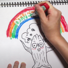 Image of a hand drawing an oak tree with a rainbow above it.